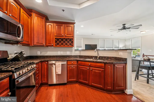 a kitchen with stainless steel appliances granite countertop a stove a sink dishwasher and a microwave oven with wooden floor