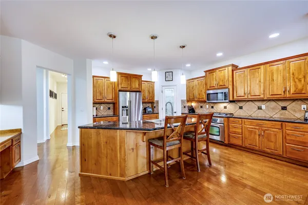 a kitchen with stainless steel appliances kitchen island granite countertop wooden floors and white cabinets