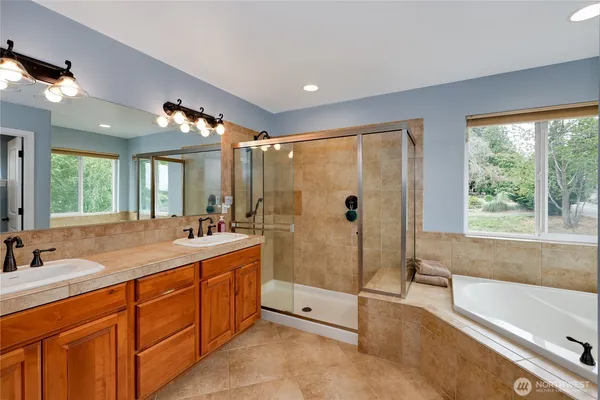 a spacious bathroom with a tub sink shower and mirror