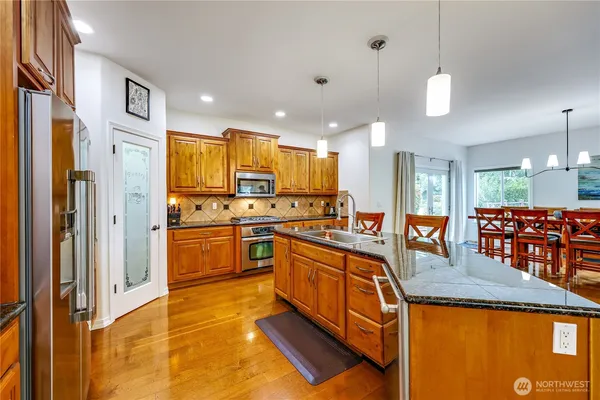 a kitchen with stainless steel appliances granite countertop a sink a stove and a refrigerator