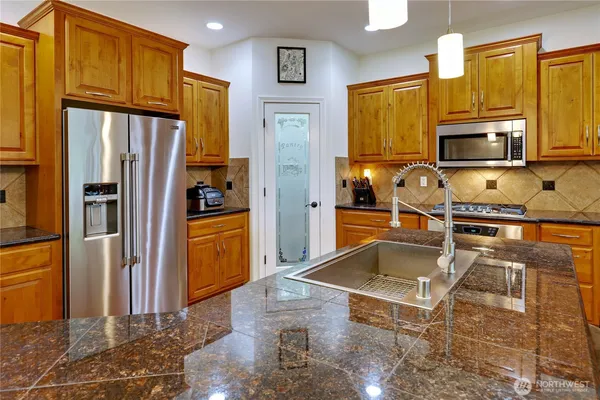 a kitchen with granite countertop a refrigerator and a sink