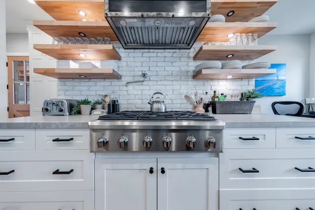 a kitchen with stainless steel appliances granite countertop a sink a stove and cabinets