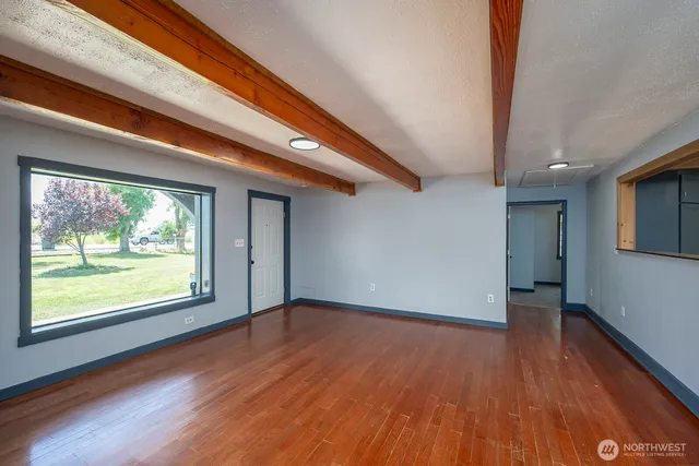 a view of an empty room with wooden floor and a window