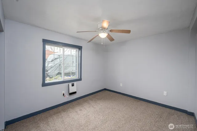 an empty room with a window and a fan