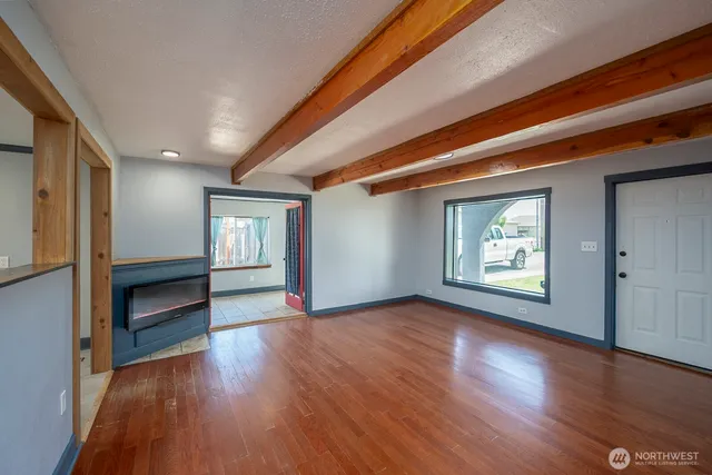 an empty room with wooden floor ceiling fan and windows