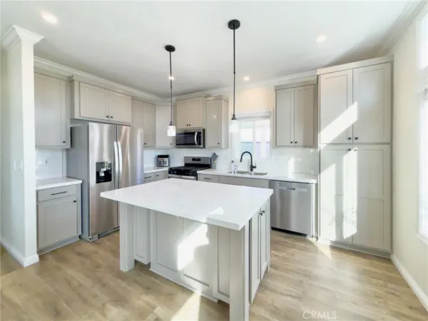 a kitchen with a sink a center island stainless steel appliances and cabinets
