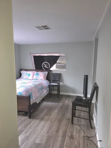 a view of an empty room with wooden floor and a bathroom