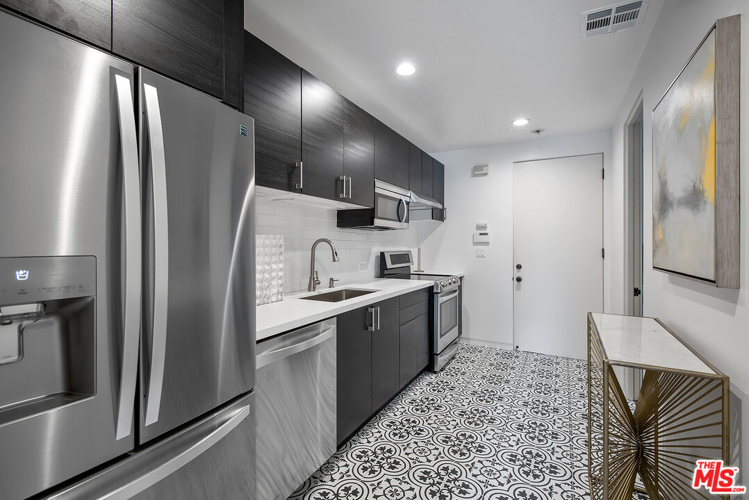 1018 Summit Drive Beverly Hills, CA 90210 - Photo 13 of 21 a kitchen with stainless steel appliances granite countertop a refrigerator and a stove top oven