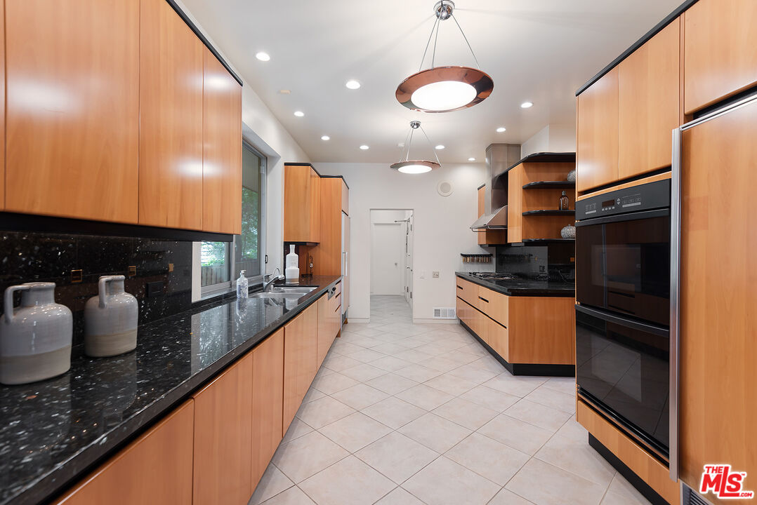 1018 Summit Drive Beverly Hills, CA 90210 - Photo 7 of 21 a large kitchen with stainless steel appliances granite countertop a sink and a refrigerator
