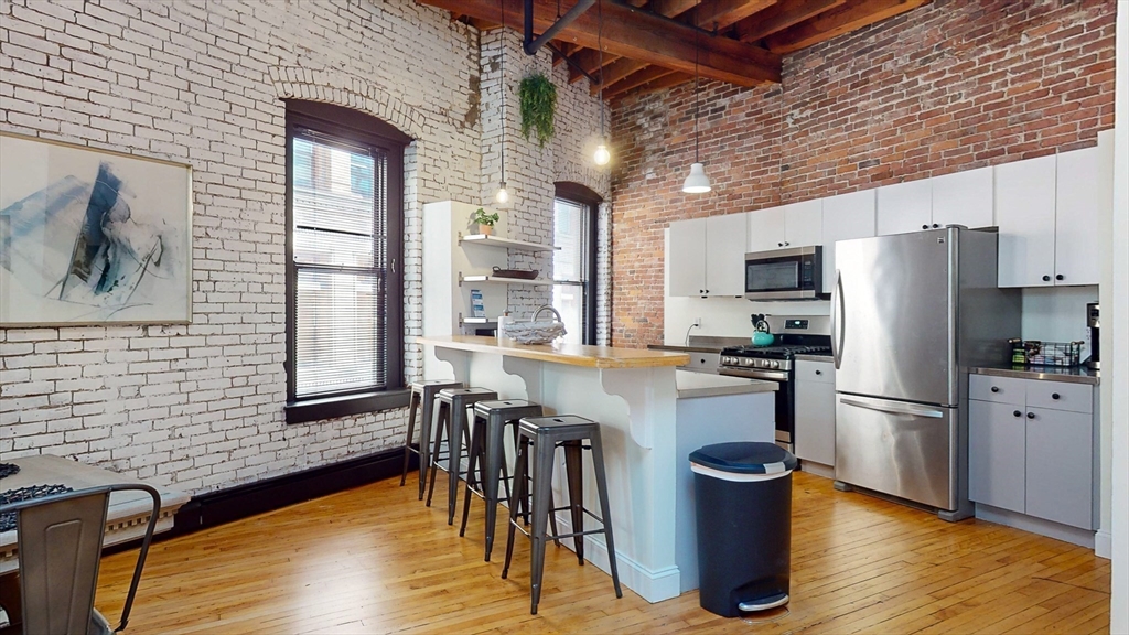 19 Stanhope Street, Unit 3A Boston, MA 02116 - Photo 17 of 19 a kitchen with stainless steel appliances a refrigerator a stove top oven a sink dishwasher and dining table with wooden floor