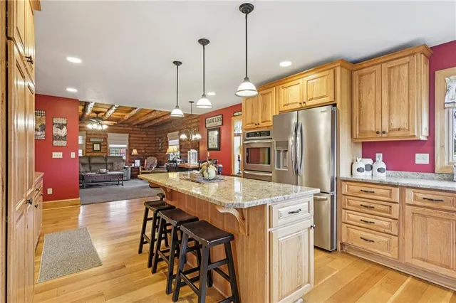 a kitchen with stainless steel appliances kitchen island granite countertop a stove a refrigerator and island with wooden floor