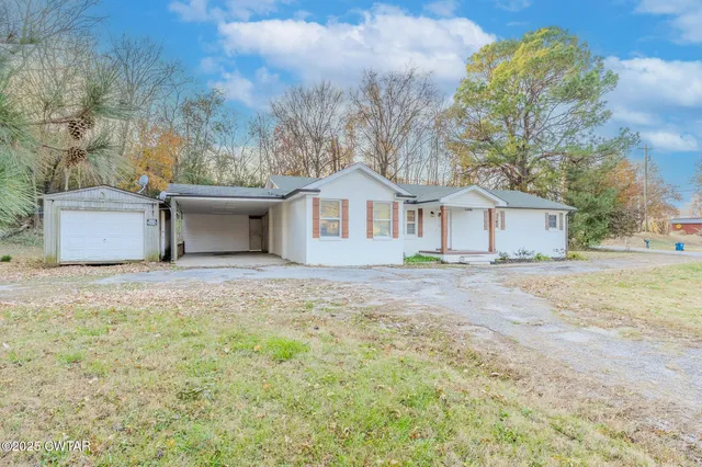 a front view of a house with a garden and tree