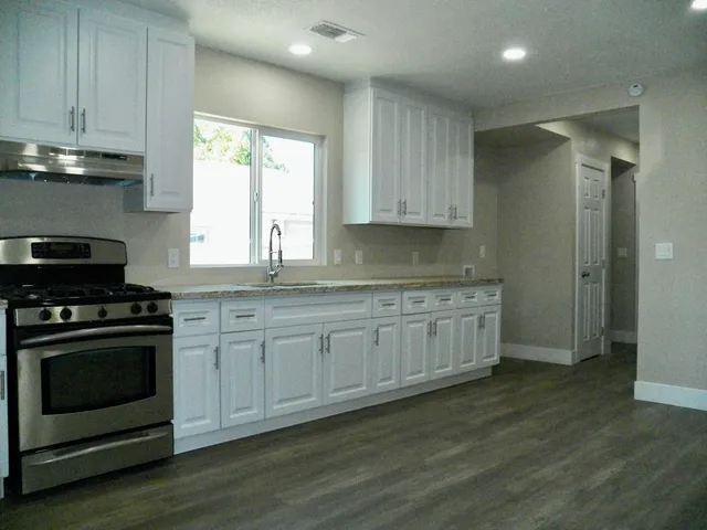 a kitchen with granite countertop wooden cabinets and a stove