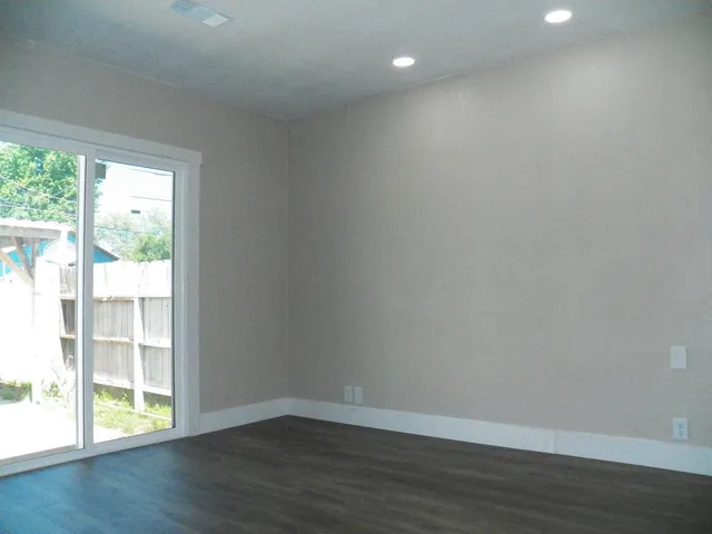 an empty room with wooden floor and windows