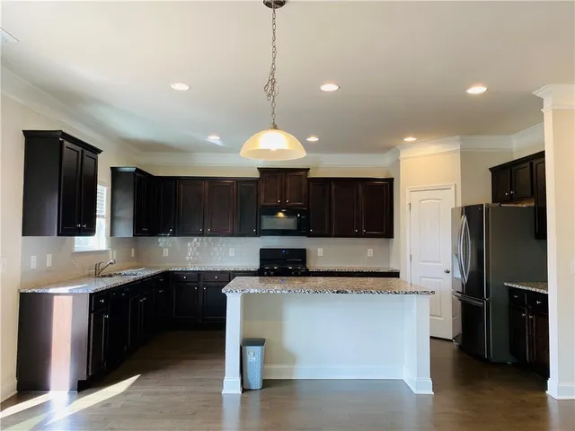 a kitchen with stainless steel appliances granite countertop a refrigerator a sink a stove a microwave and wooden cabinets