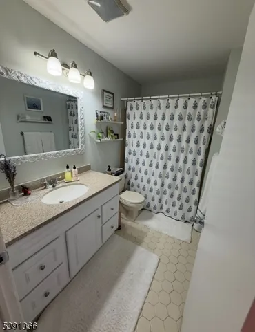 a bathroom with a granite countertop sink a toilet a mirror and shower