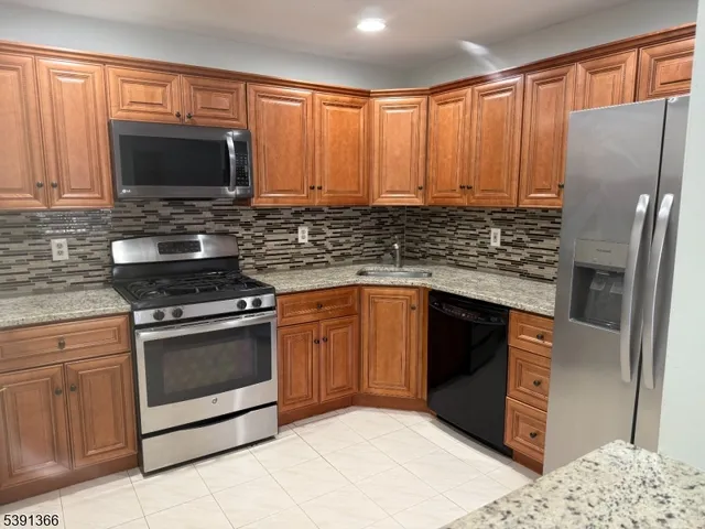 a kitchen with granite countertop a stove top oven microwave and cabinets