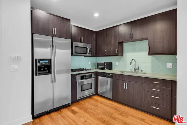 a large kitchen with stainless steel appliances granite countertop a stove a sink and a refrigerator