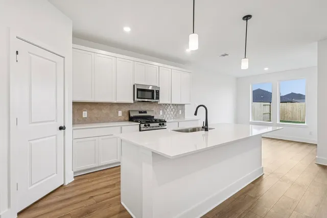 a kitchen with white cabinets and sink