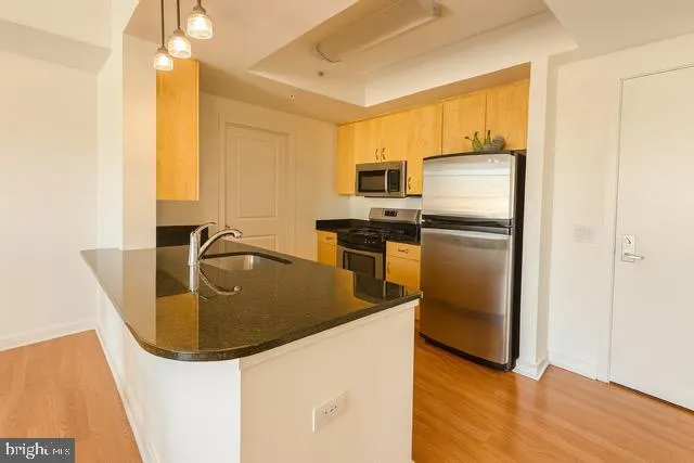 a kitchen with stainless steel appliances granite countertop a sink a stove and a refrigerator
