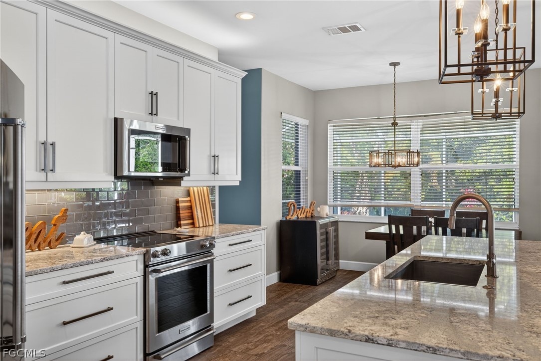 22866 Forest Ridge Drive Estero, FL 33928 - Photo 6 of 38 a kitchen with stainless steel appliances granite countertop a stove a sink and a granite counter tops with wooden floors