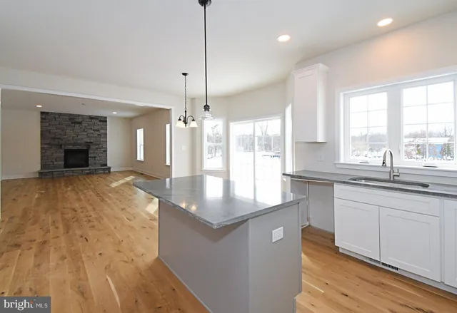 a kitchen with stainless steel appliances granite countertop a sink a stove and a wooden floors