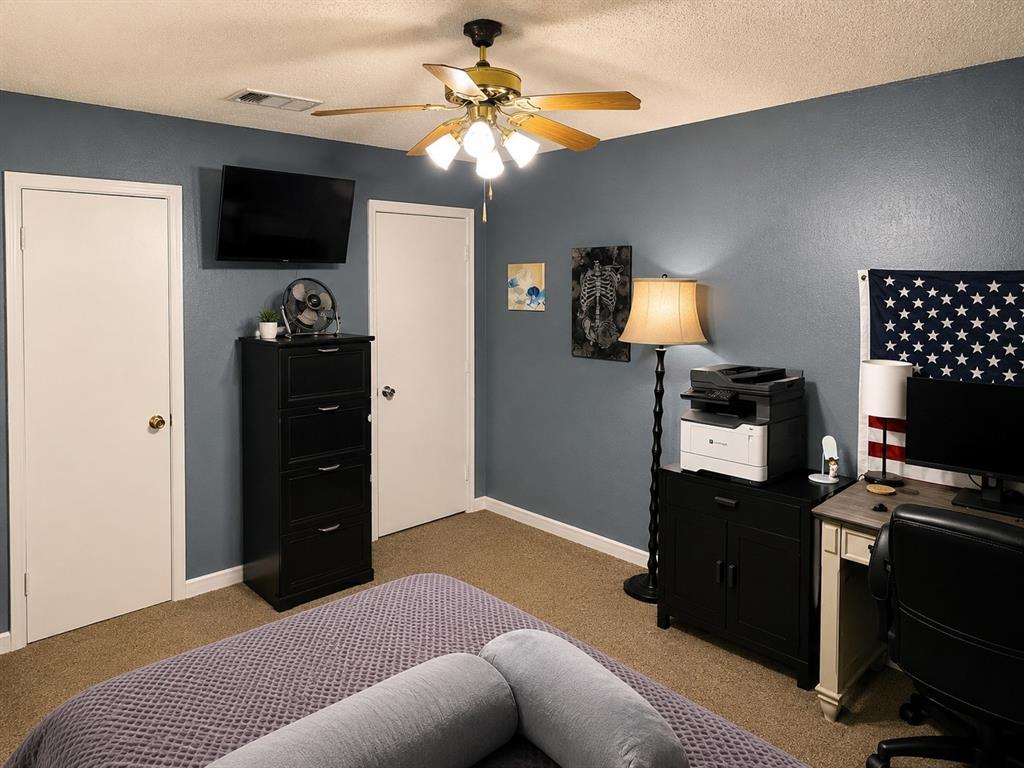 511 Rogers Road Newark, TX 76071 - Photo 13 of 22 Interior room featuring a ceiling fan with integrated lighting, two white panel doors, and neutral carpet flooring