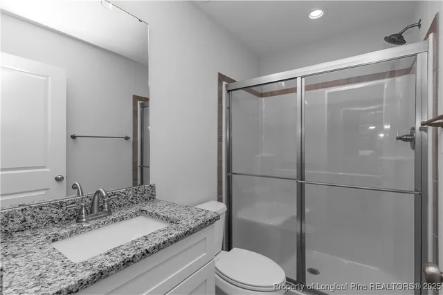 a bathroom with a granite countertop sink a toilet and shower