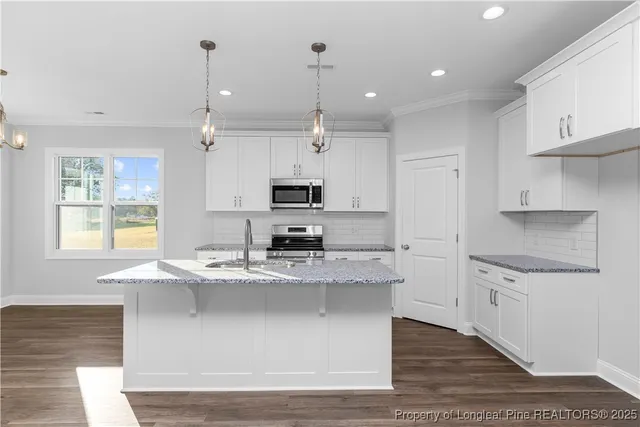 a kitchen with granite countertop a sink stainless steel appliances and white cabinets