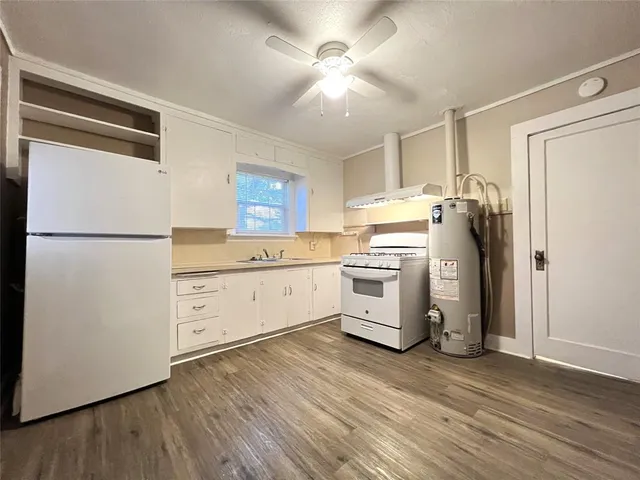 a kitchen with a refrigerator a stove top oven a sink and dishwasher with wooden floor