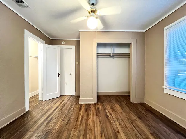 a view of empty room with wooden floor and fan