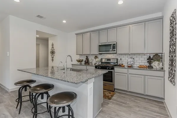 a kitchen with granite countertop a sink and a stove top oven with wooden floor