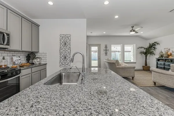 a large kitchen with a stove a sink a counter space and cabinets
