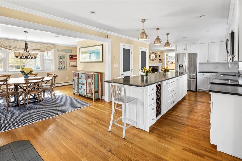 26 Stanford Drive Hingham, MA 02043 - Photo 8 of 37 a large kitchen with stainless steel appliances kitchen island granite countertop a large island a stove a dining table and chairs with wooden floor