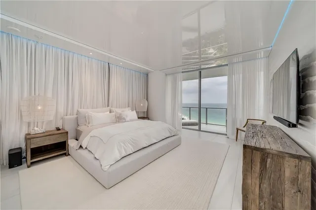 a bedroom with a bed a flat tv screen and a large window with the garden view