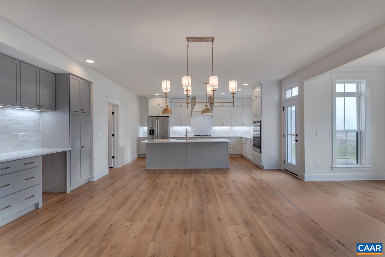3031 Eagle View Charlottesville, VA 22903 - Photo 25 of 75 a large kitchen with kitchen island a stove a refrigerator a sink dishwasher and white cabinets with wooden floor