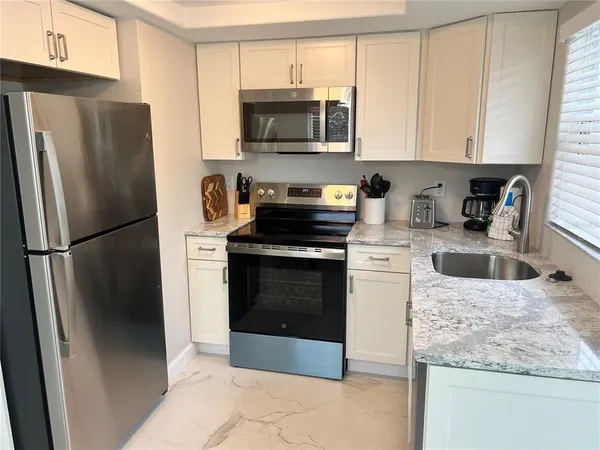 a kitchen with granite countertop a refrigerator stove and microwave