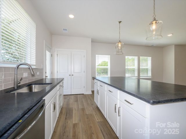 a kitchen with granite countertop a sink a counter space appliances and windows
