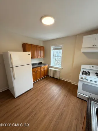 a kitchen with a refrigerator a stove top oven a sink dishwasher and wooden floor