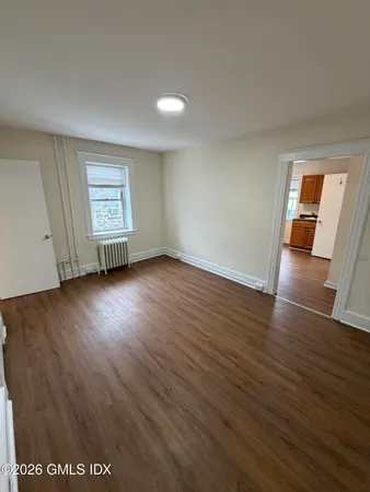 a view of an empty room with wooden floor and a window