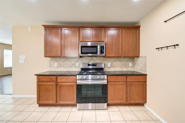 a kitchen with stainless steel appliances granite countertop a stove a sink and a microwave