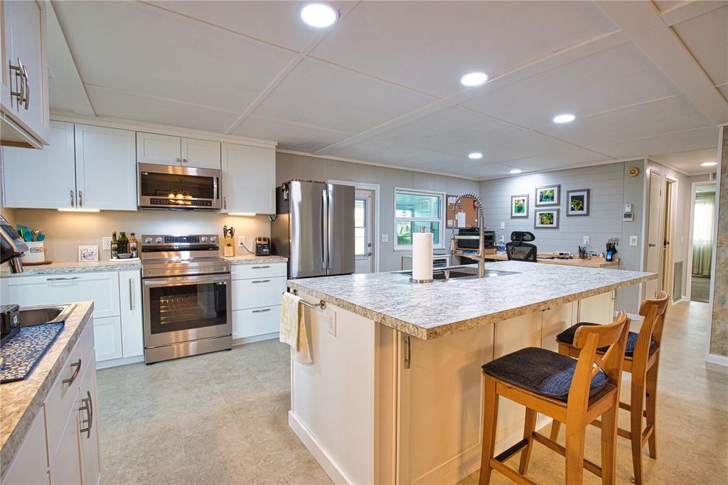 674 El Tango North Port, FL 34287 - Photo 11 of 85 a kitchen with stainless steel appliances granite countertop a stove top oven a sink dishwasher a dining table and chairs with wooden cabinets