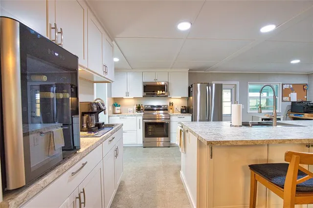 a kitchen with stainless steel appliances granite countertop a stove top oven a sink dishwasher a dining table and chairs with wooden cabinets