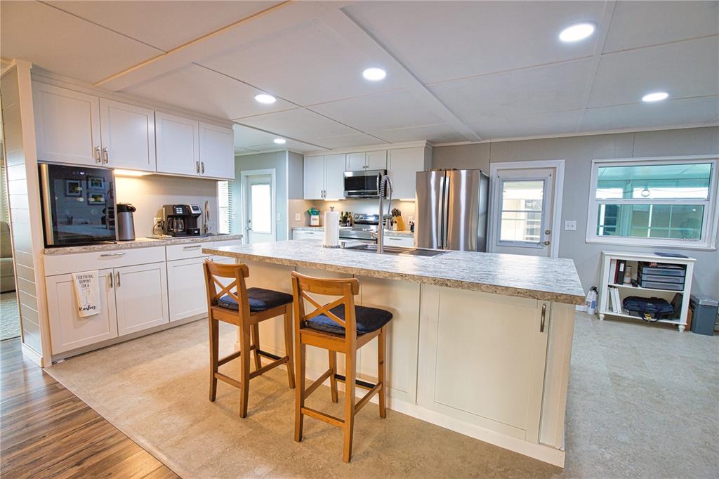 674 El Tango North Port, FL 34287 - Photo 10 of 85 a kitchen with stainless steel appliances granite countertop a stove top oven a sink dishwasher and white cabinets with wooden floor