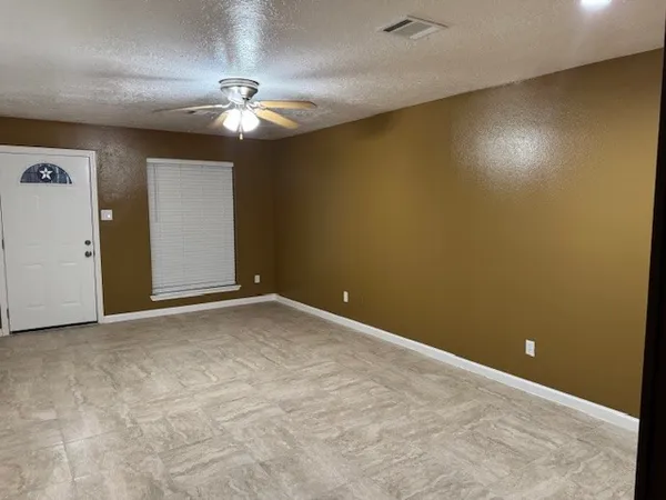 an empty room with a window and a fan