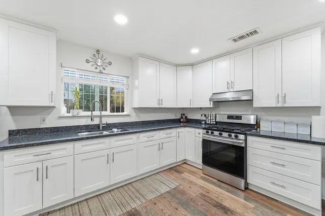 a kitchen with granite countertop white cabinets and appliances