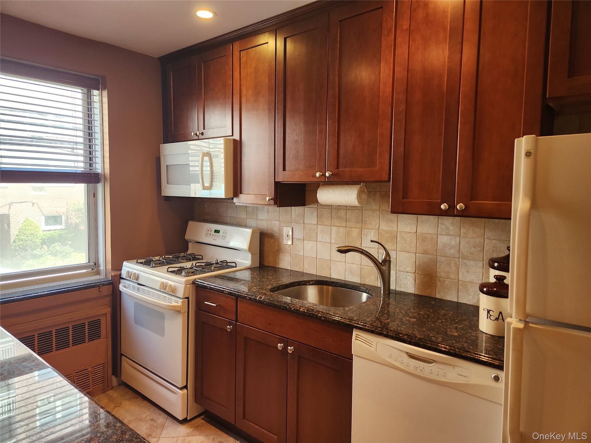 700 Shore Road, Unit 2U Long Beach, NY 11561 - Photo 8 of 24 Kitchen with white appliances, healthy amount of natural light, radiator heating unit, and Granite Counter tops. View 1