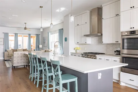 a kitchen with a dining table chairs wooden floor cabinets and stainless steel appliances