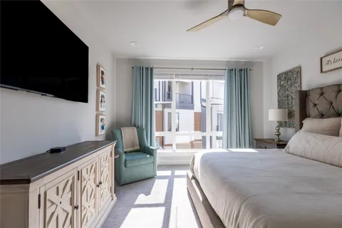 a spacious bedroom with a bed and a flat tv screen on dresser