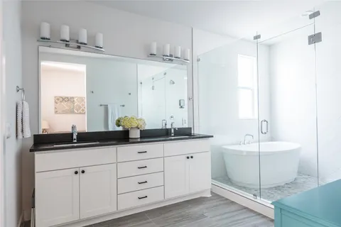 a bathroom with a double vanity sink mirror and bathtub